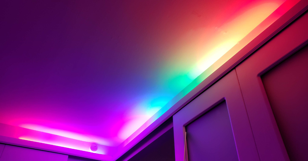 Colorful strip light along the ceiling of a room.