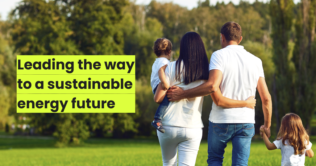 Young couple with two children walking towards a park filled with trees and grass.